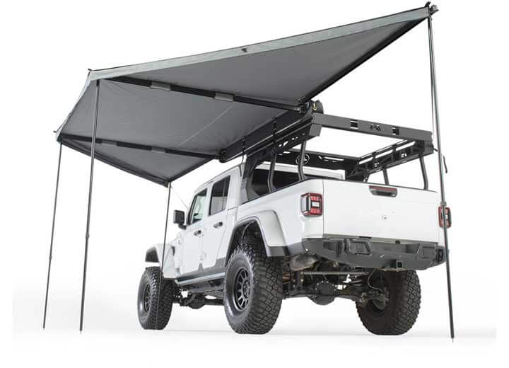 Smittybilt 180° awning providing shade over a white off-road vehicle with a roof rack.