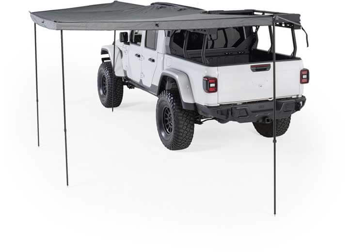 Smittybilt 180° awning providing shade over a white off-road vehicle, designed for rugged outdoor use.