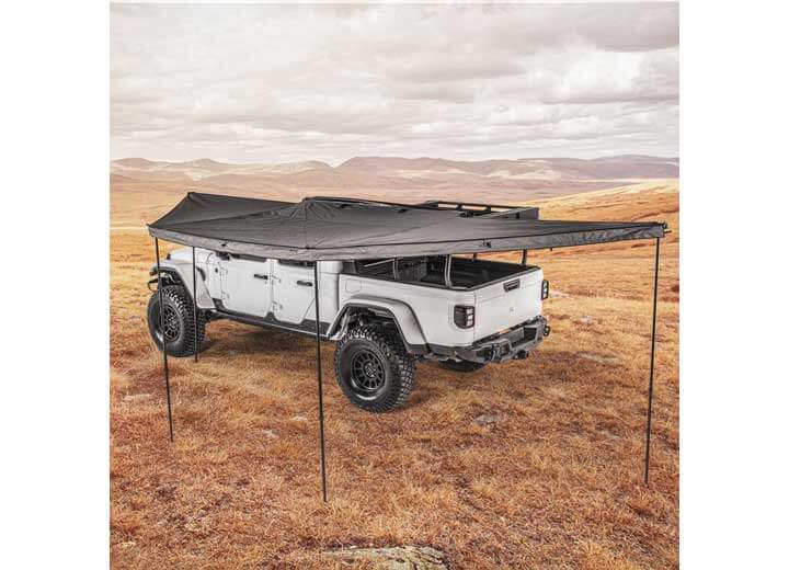 Smittybilt 180° Awning providing shade for off-road vehicle in open landscape.
