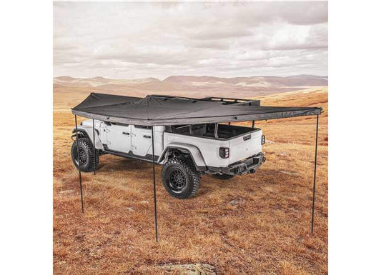 Smittybilt 180° Awning providing shade for off-road vehicle in open landscape.
